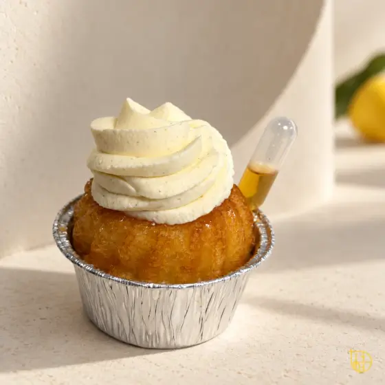 Baba au rhum avec crème montée à la vanille et pipette, sur un décor ivoire